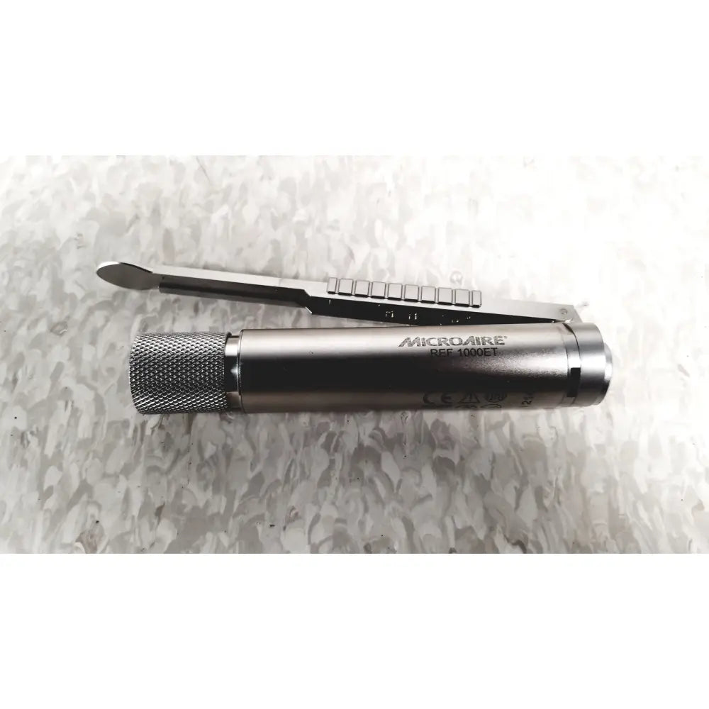 Silver metallic microaire surgical instrument with textured grip and engraved branding for precise surgical use