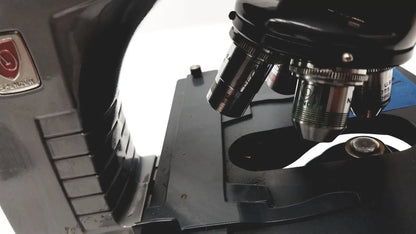 Black metal microscope american optical spencer with silver-toned objective lenses and red logo plaque on the side