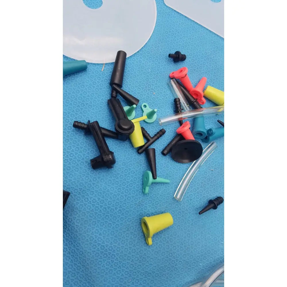 A collection of colorful plastic and clear tubing connectors on a blue surface from the mityvac mv8500 elite automotive kit