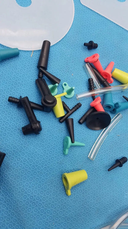 A collection of colorful plastic and clear tubing connectors on a blue surface from the mityvac mv8500 elite automotive kit