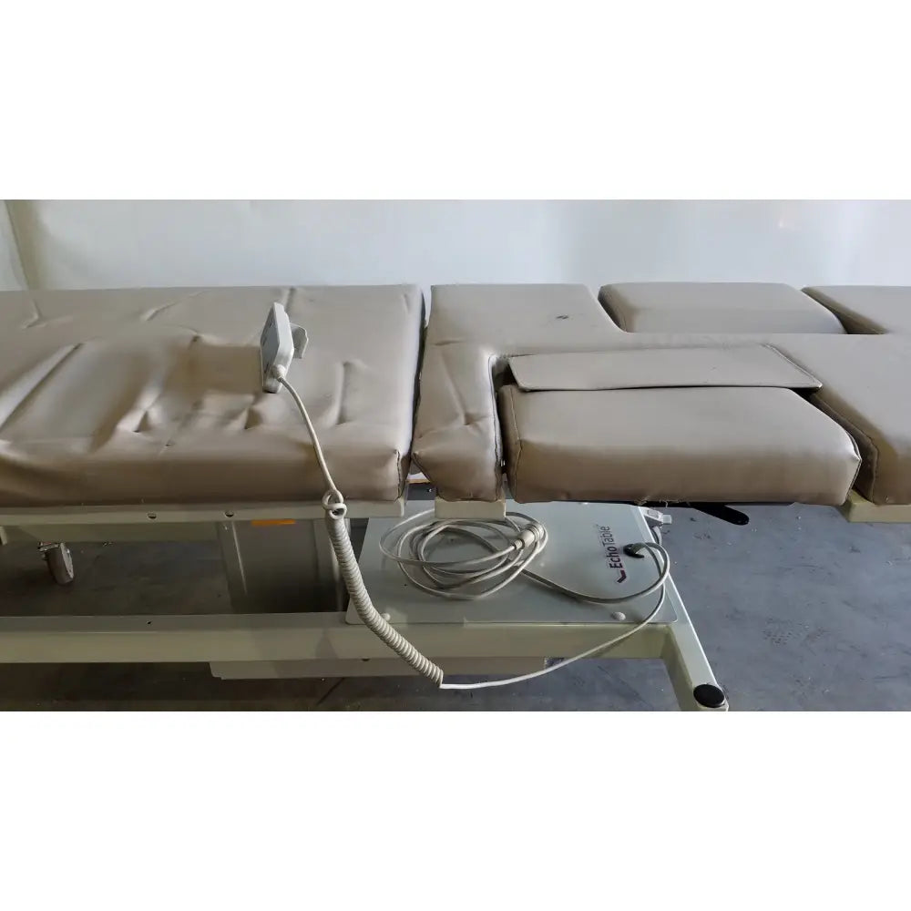 Beige mpi imaging table model 251 echo table with adjustable segmented padded sections and coiled power cord on base