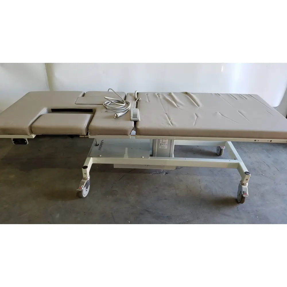 Beige upholstered mpi imaging table model 251 echo table with segmented padded sections and caster wheels for medical use