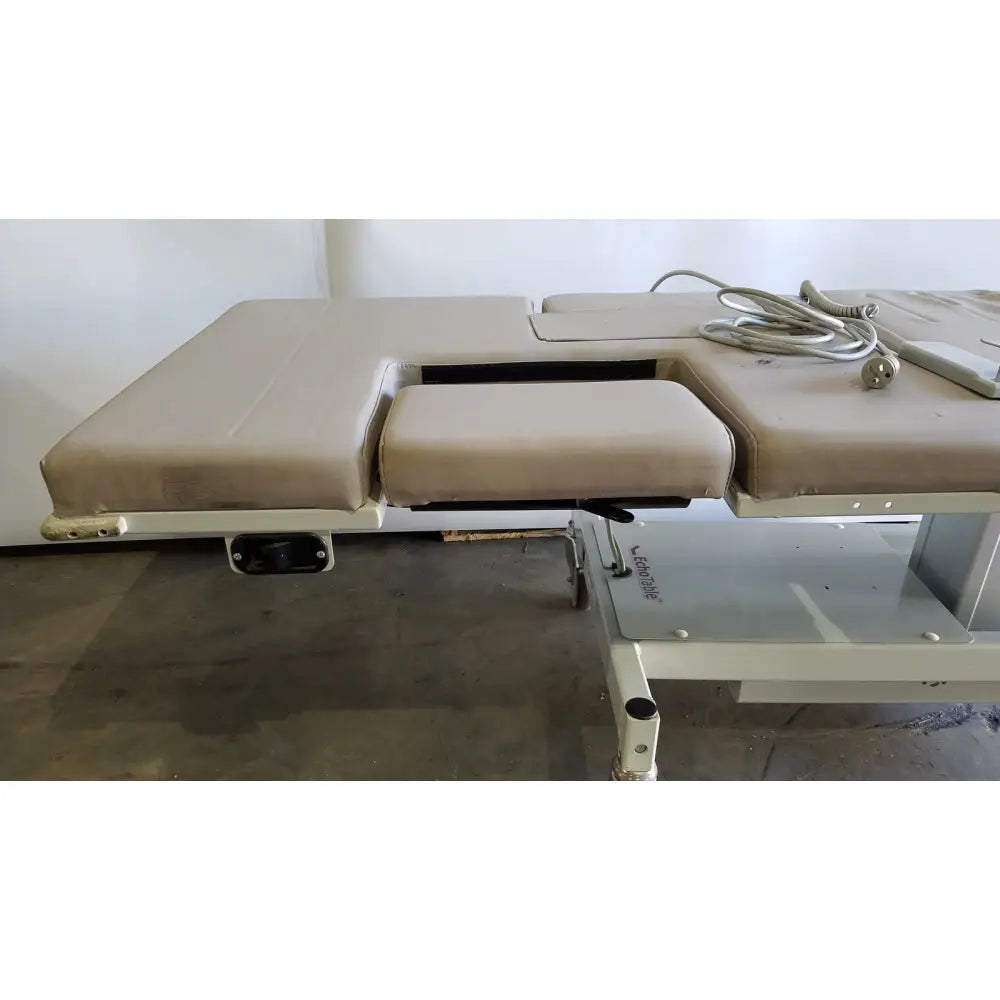 Beige upholstered electric mpi imaging table model 251 echo table with segmented padding and metallic frame with TH2 handset