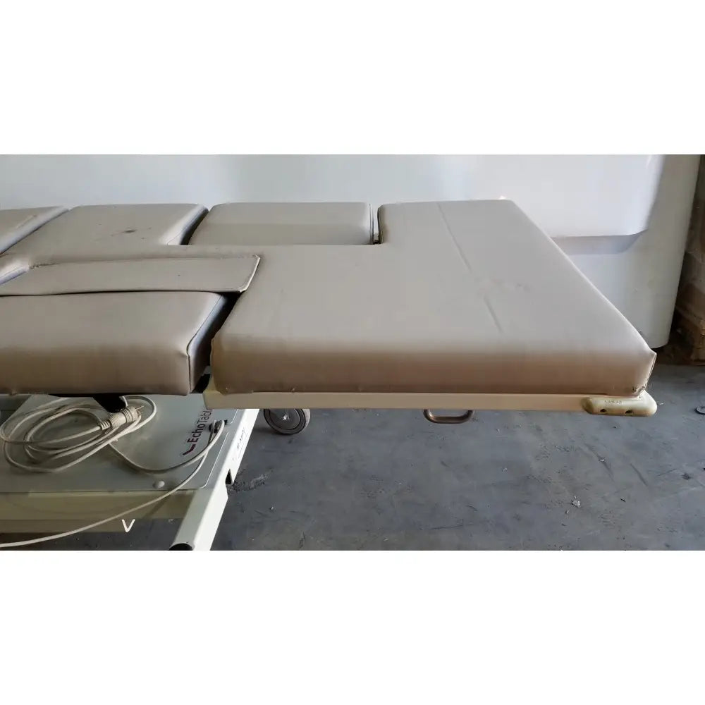 Beige padded mpi imaging table model 251 echo table with segmented cushioning and metal frame with th2 handset