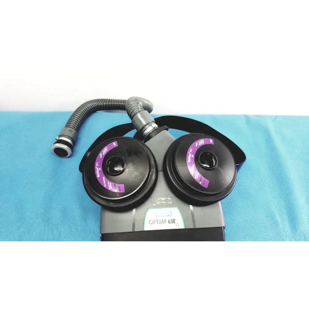 Gray and black msa optimair tl papr blower unit with two purple-labeled filter cartridges connected by flexible hose