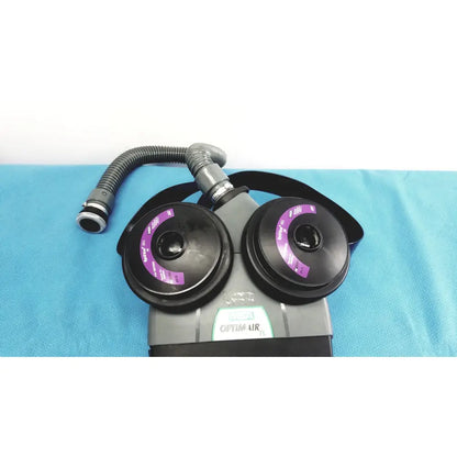 Gray and black msa optimair tl papr blower unit with two purple-labeled filter cartridges connected by flexible hose
