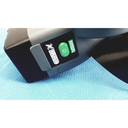 Black and gray MSA optimair TL PAPR blower unit with green button and battery for respiratory protection systems