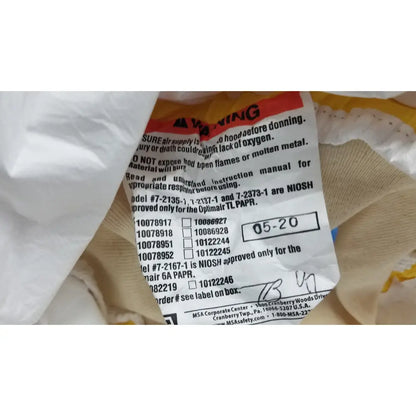 Warning label on the back of msa yellow safety respirator s-cap hood with black text, red header, and barcode