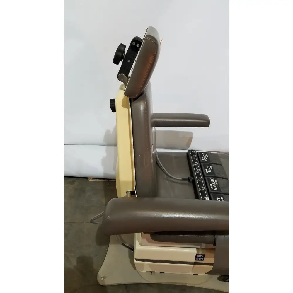 Brown leather-backed mti programmable podiatry chair with beige metal frame and foot control panel visible from the back side
