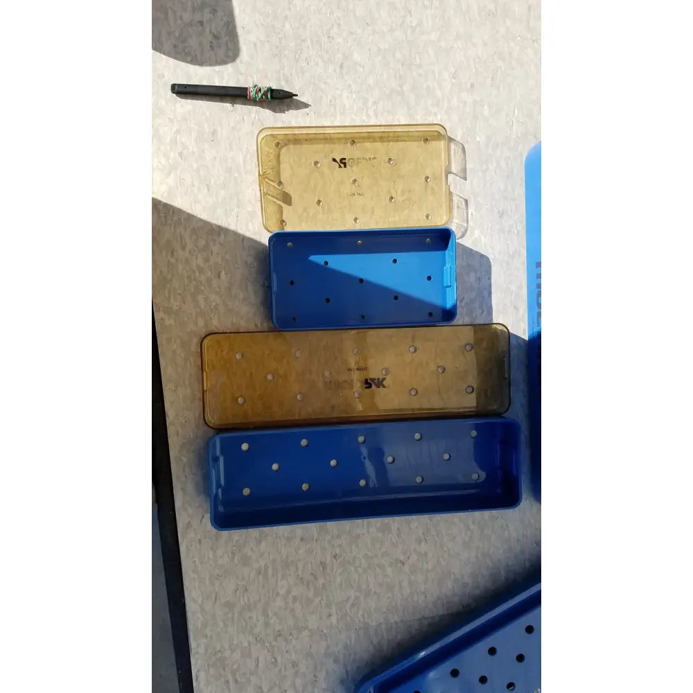 Stacked blue and translucent yellow plastic sterilization trays with circular holes for tools multipak 5006-02-000p