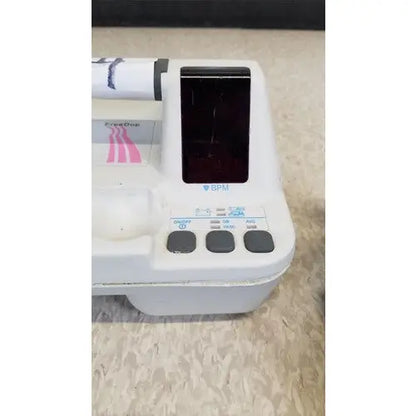White plastic ECG machine Natus Neurology Freedop XLD004 with black screen and pink striped paper roll