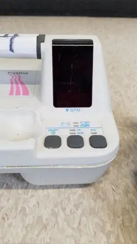 White plastic ECG machine Natus Neurology Freedop XLD004 with black screen and pink striped paper roll