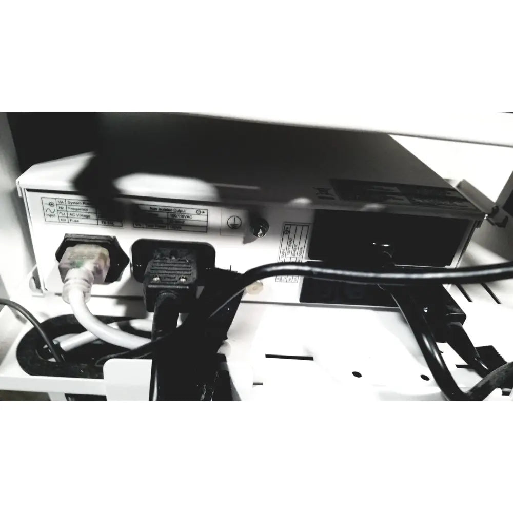 White electronic device with two power plugs and black cables connected at the back of natus neurology nicolet edx base system cart