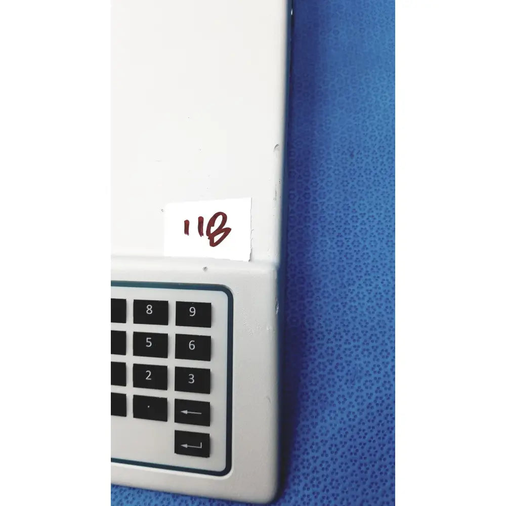 White plastic keypad with black numbered buttons and arrows on a blue surface on natus ultrapro s100 unit control panel