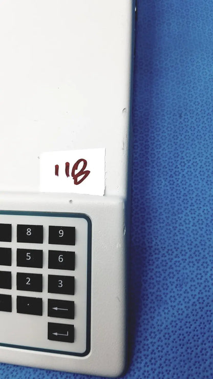 White plastic keypad with black numbered buttons and arrows on a blue surface on natus ultrapro s100 unit control panel