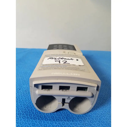 Gray plastic nellcor puritan bennett portable pulse oximeter with black control panel and multiple ports back side view
