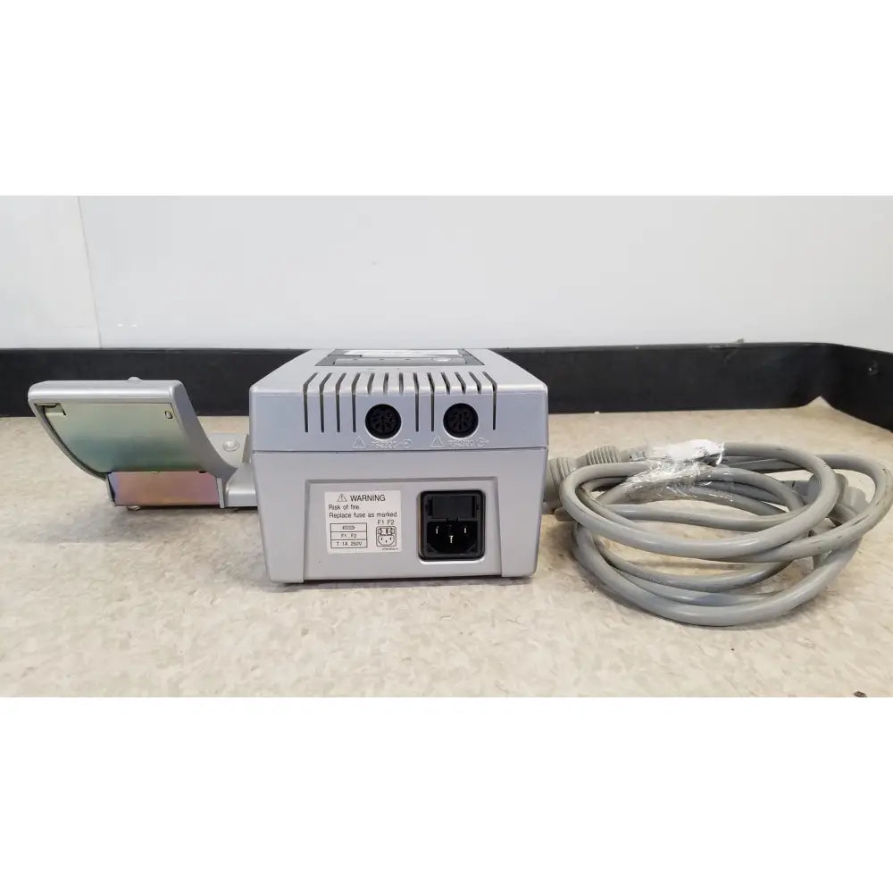 Gray rectangular power adapter with coiled cable and metallic component for nidek ar-20st1 handheld autorefractor printer