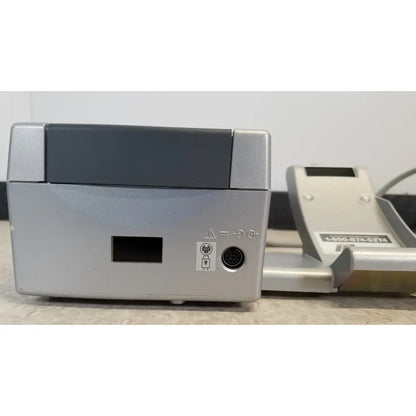 Back side of silver nidek ar-20st1 handheld autorefractor printer with dark gray top panel and circular port