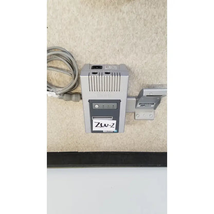 Gray and black zw-2 power adapter with coiled cable mounted on wall bracket for nidek ar-20st1 handheld autorefractor printer