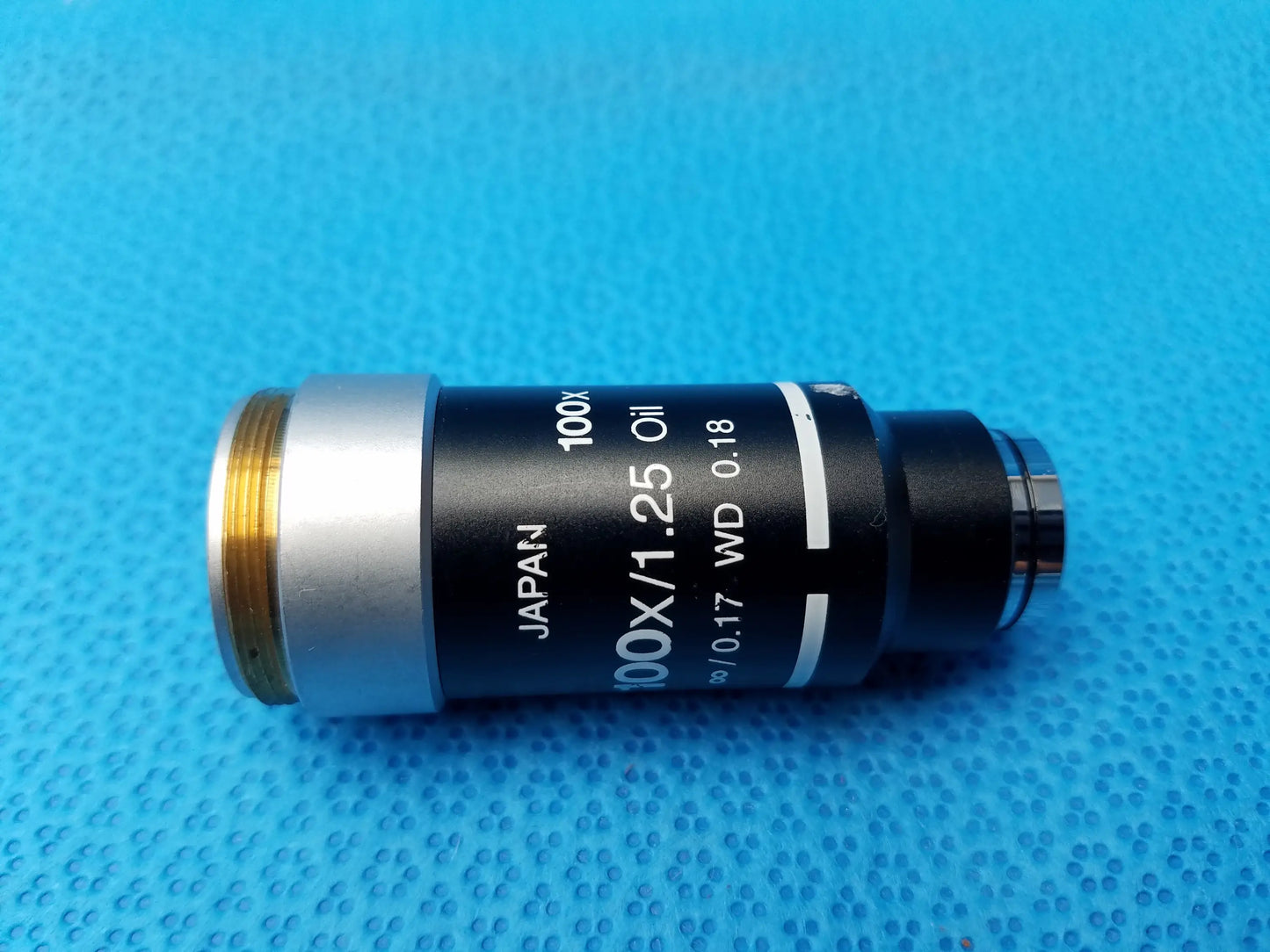 Black and silver Nikon 100x oil microscope objective with gold threading and 1.25 numerical aperture for compatible Nikon microscope