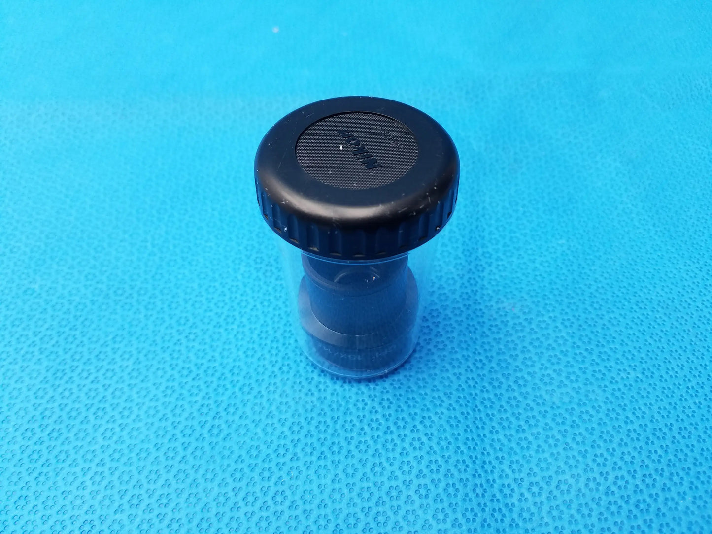 Black plastic cap with textured grip and mesh top sealed over clear container for nikon cfi 15x microscope eyepiece storage