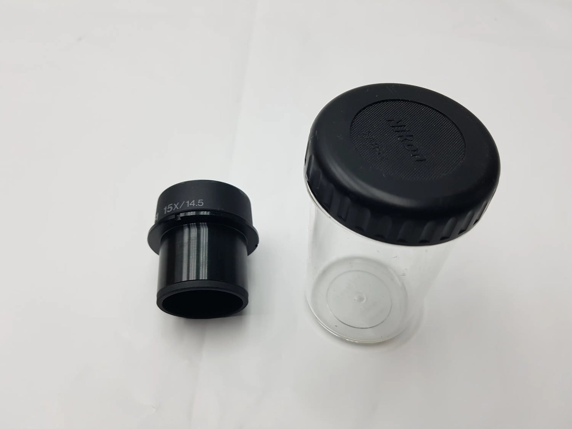 Black Nikon CFI 15x 14.5 eyepiece with clear plastic storage case and black ribbed lid compatible with Nikon microscope systems