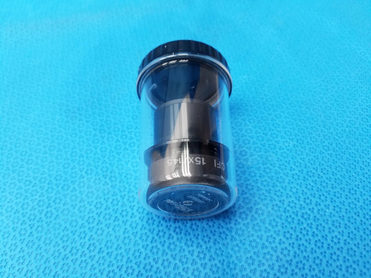 Black cylindrical nikon cfi 15x microscope eyepiece with engraved field number and clear protective storage case