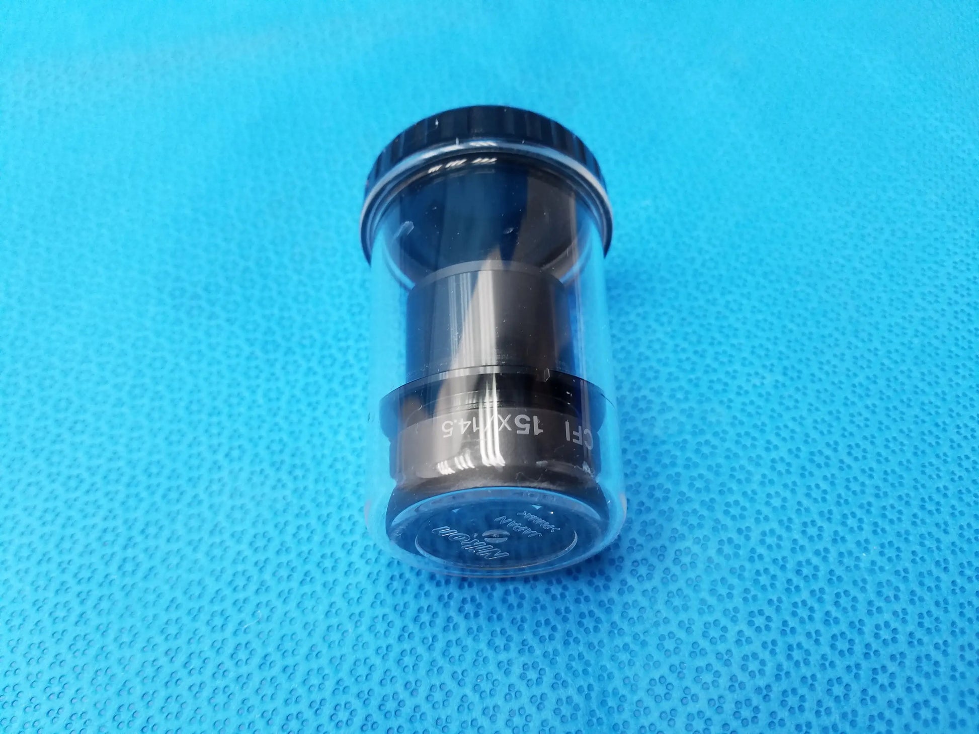 Black cylindrical nikon cfi 15x microscope eyepiece with engraved field number and clear protective storage case