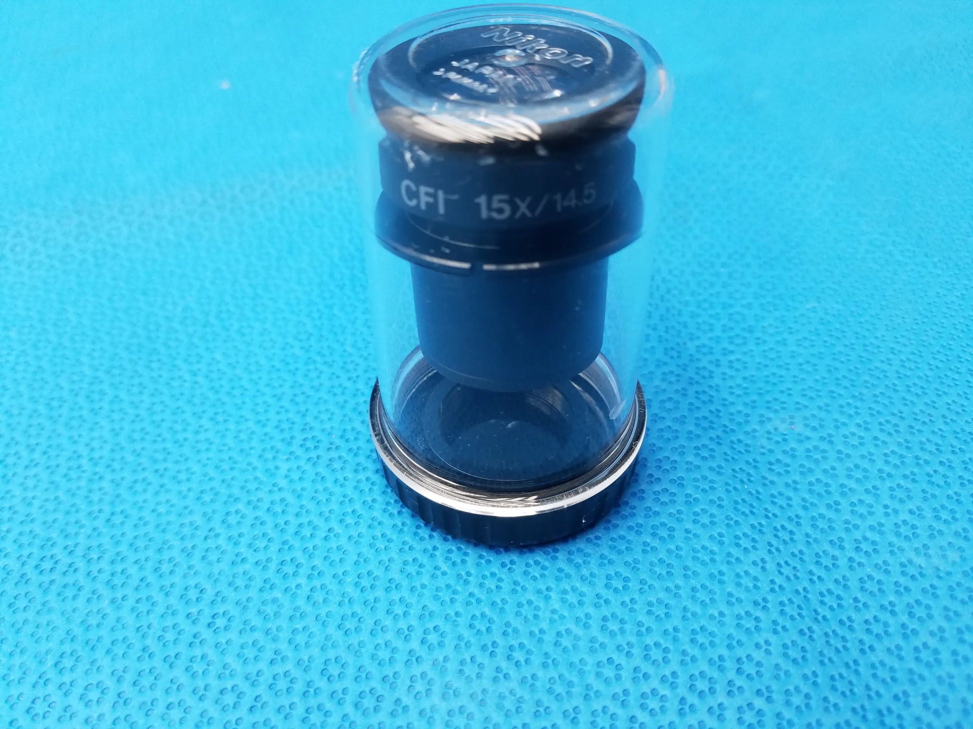 Black and silver nikon cfi 15x microscope eyepiece with field number 14.5 in clear protective storage case