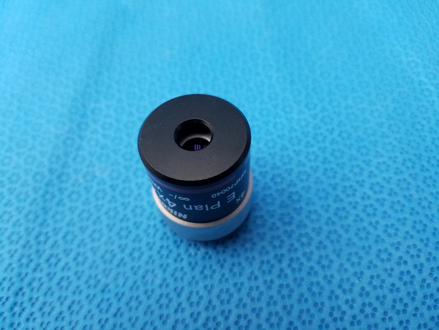 Black and silver Nikon E Plan microscope objective lens with numerical aperture 0.10 and matte black top cap