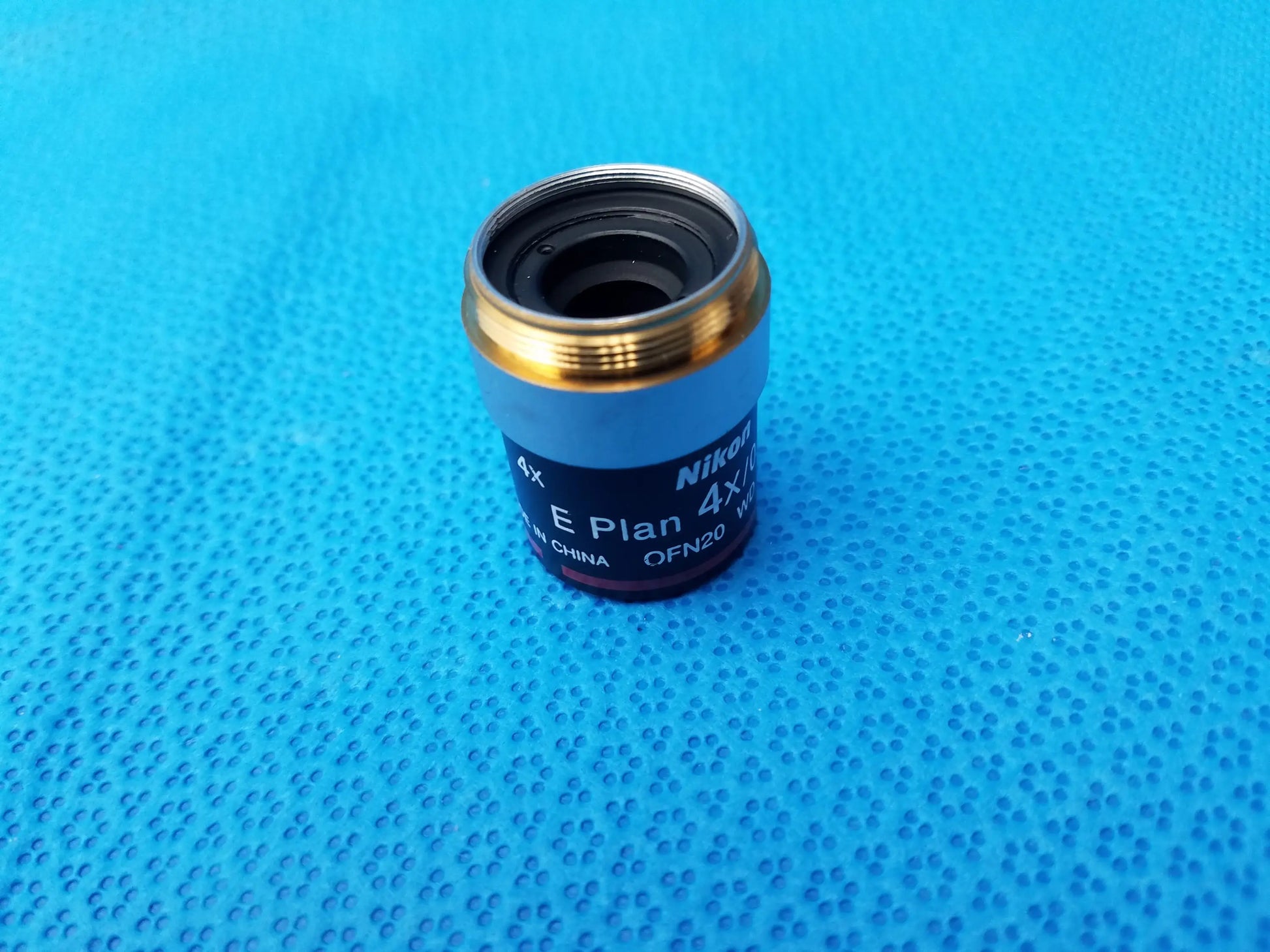 Nikon e plan 4x microscope objective lens with numerical aperture 0.10, metallic gold rim, and black body for microscopy