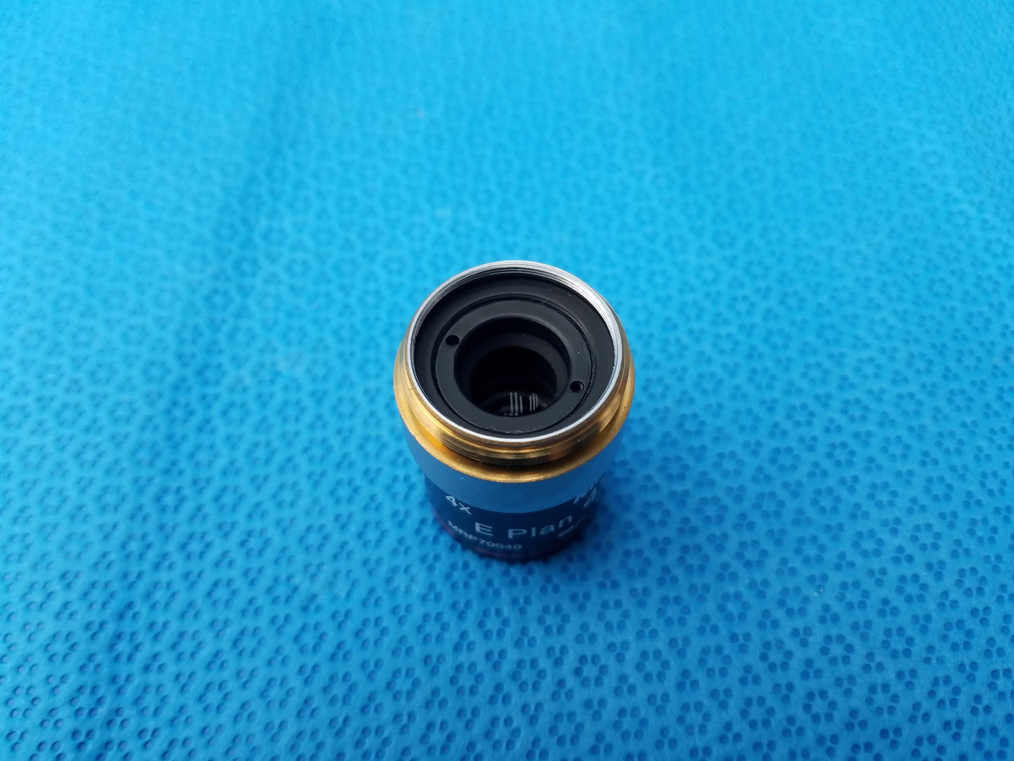 Blue and gold Nikon E Plan microscope objective lens with black interior ring and numerical aperture 0.10 for precision use