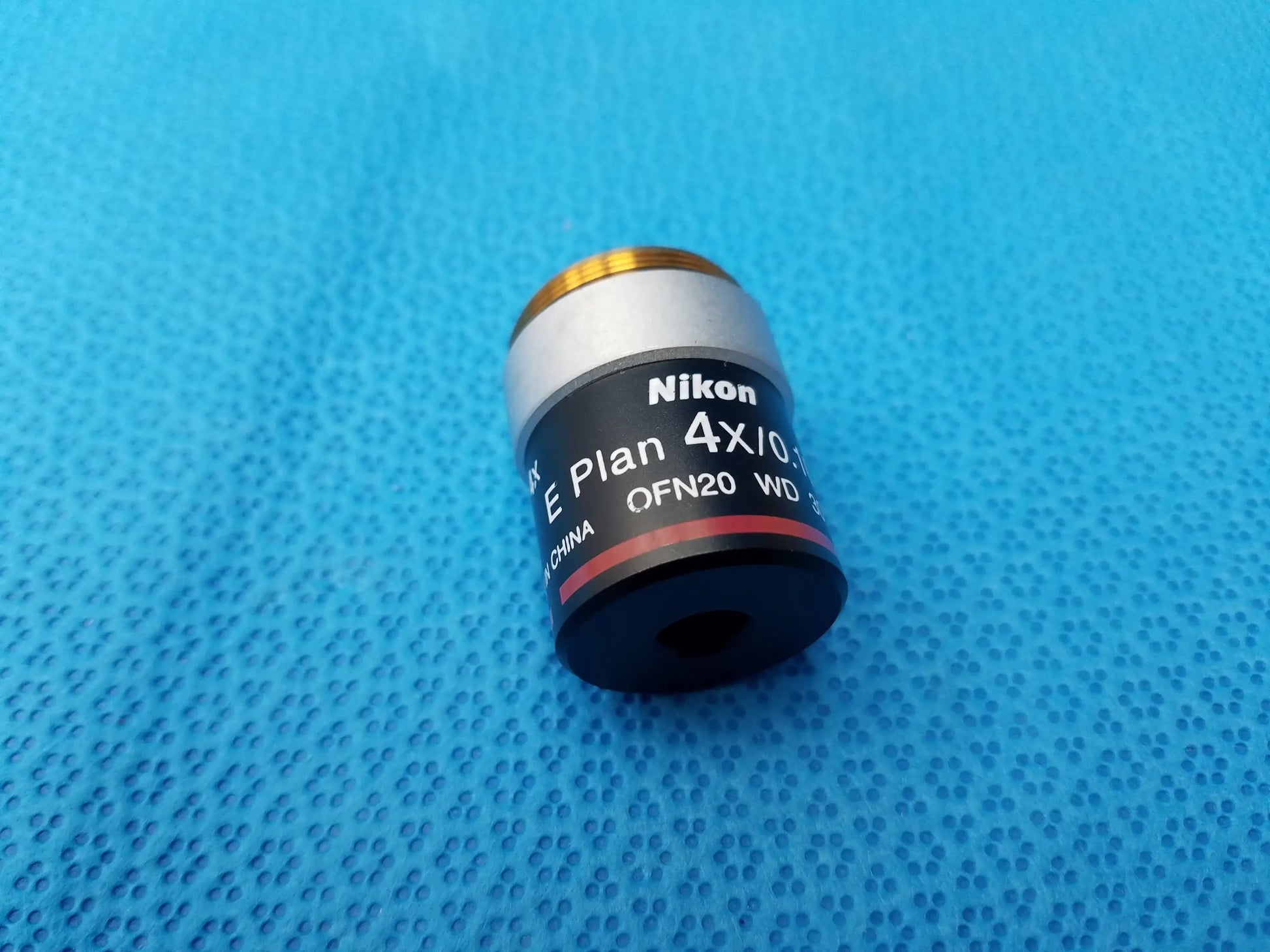 Nikon e plan 4x microscope objective with numerical aperture 0.10 features a silver metal body and gold threaded top