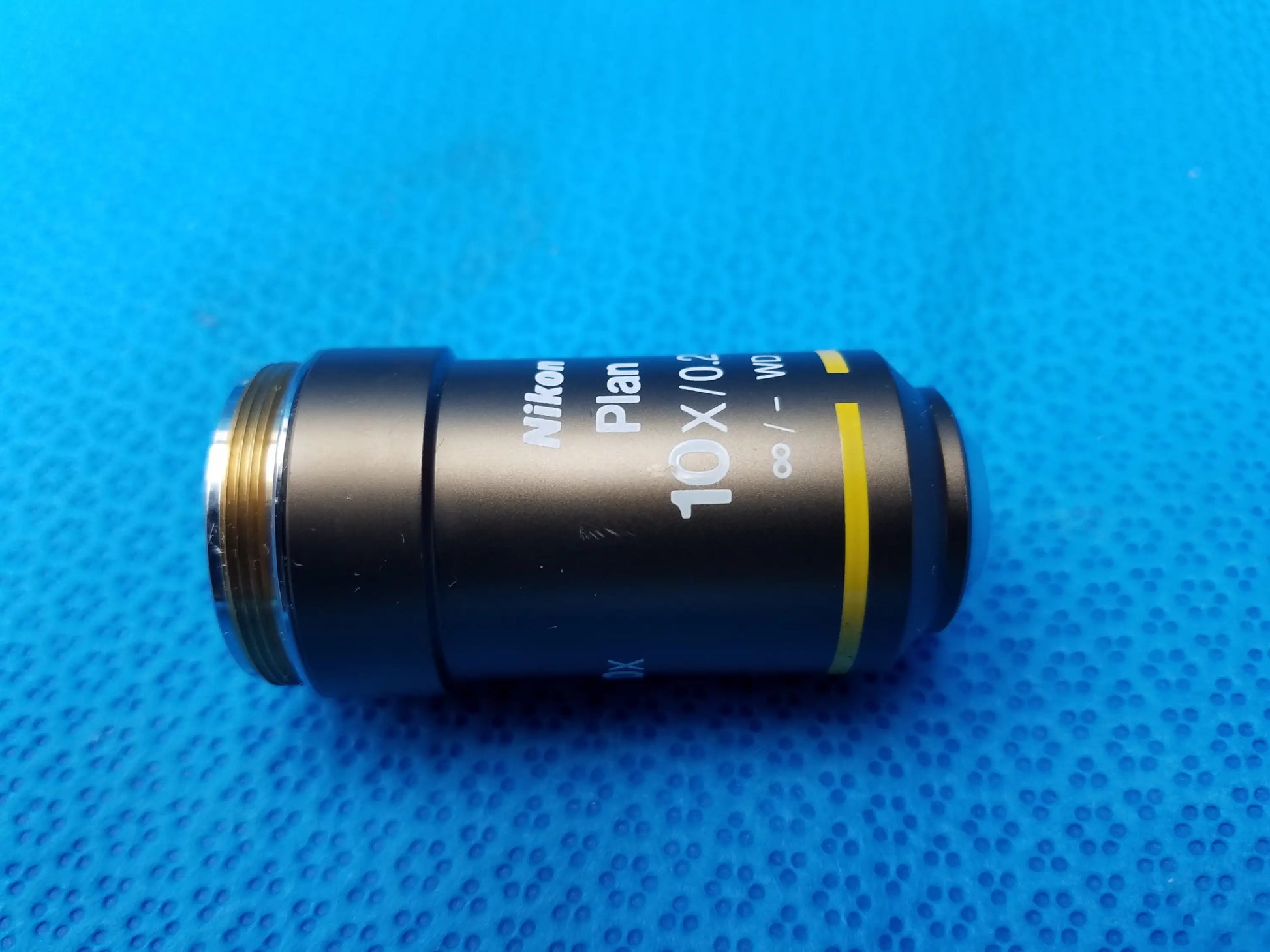 Black Nikon Plan 10X 0.25 microscope objective with yellow stripe and metallic threading for compatible Nikon microscope systems