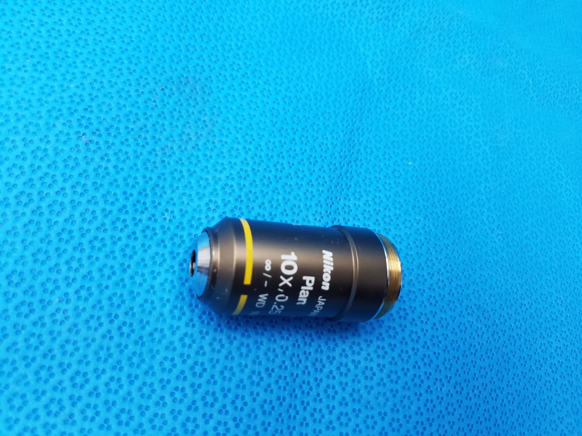 Black Nikon Plan 10x/0.25 microscope objective lens with gold threaded mount and yellow stripe for compatible Nikon microscope systems
