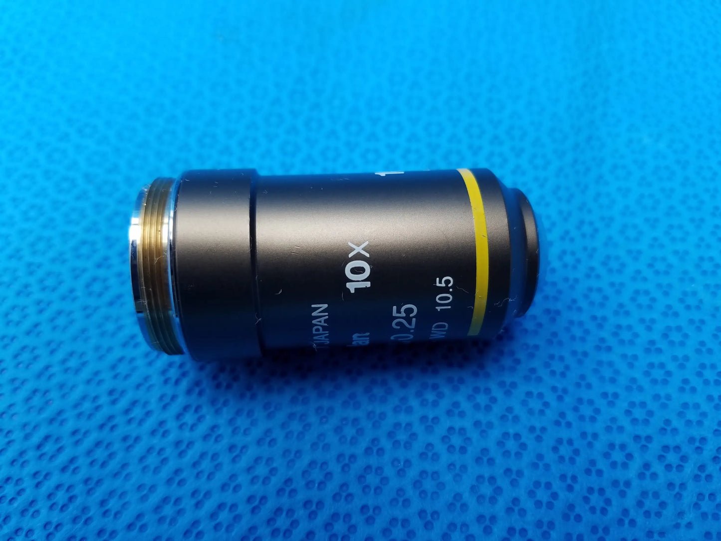 Black cylindrical nikon plan 10x 025 microscope objective lens with yellow ring and metallic threading for compatible nikon microscope systems