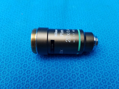 Black Nikon Plan 20x microscope objective lens with gold threaded mount and green accent ring for precise imaging