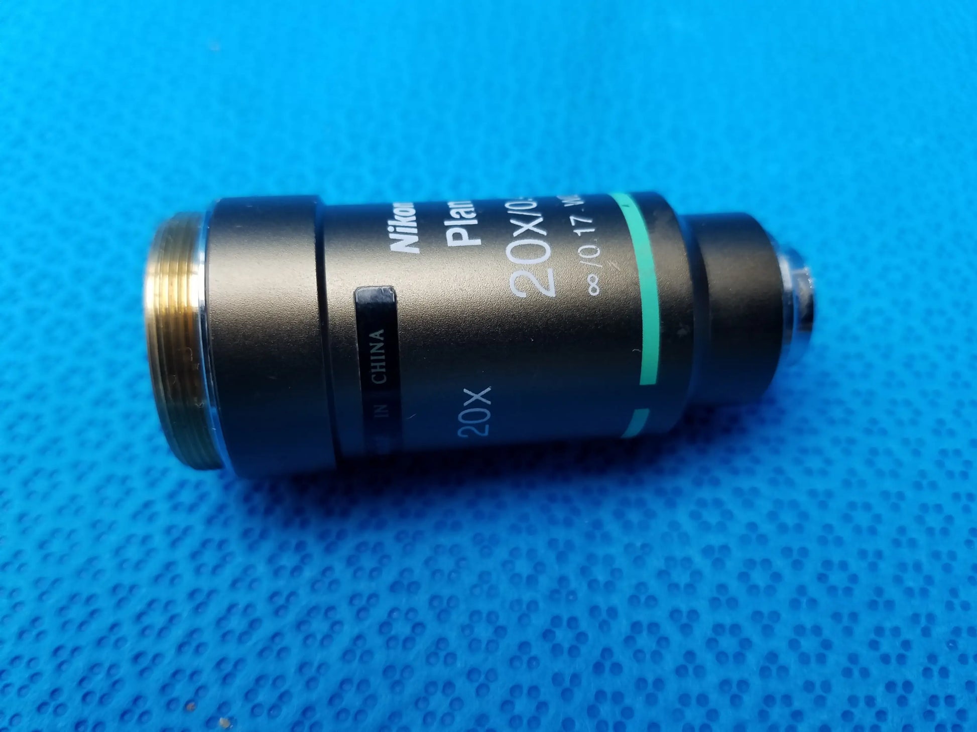 Black Nikon Plan 20x microscope objective lens with gold threading and green accent stripe for precise imaging
