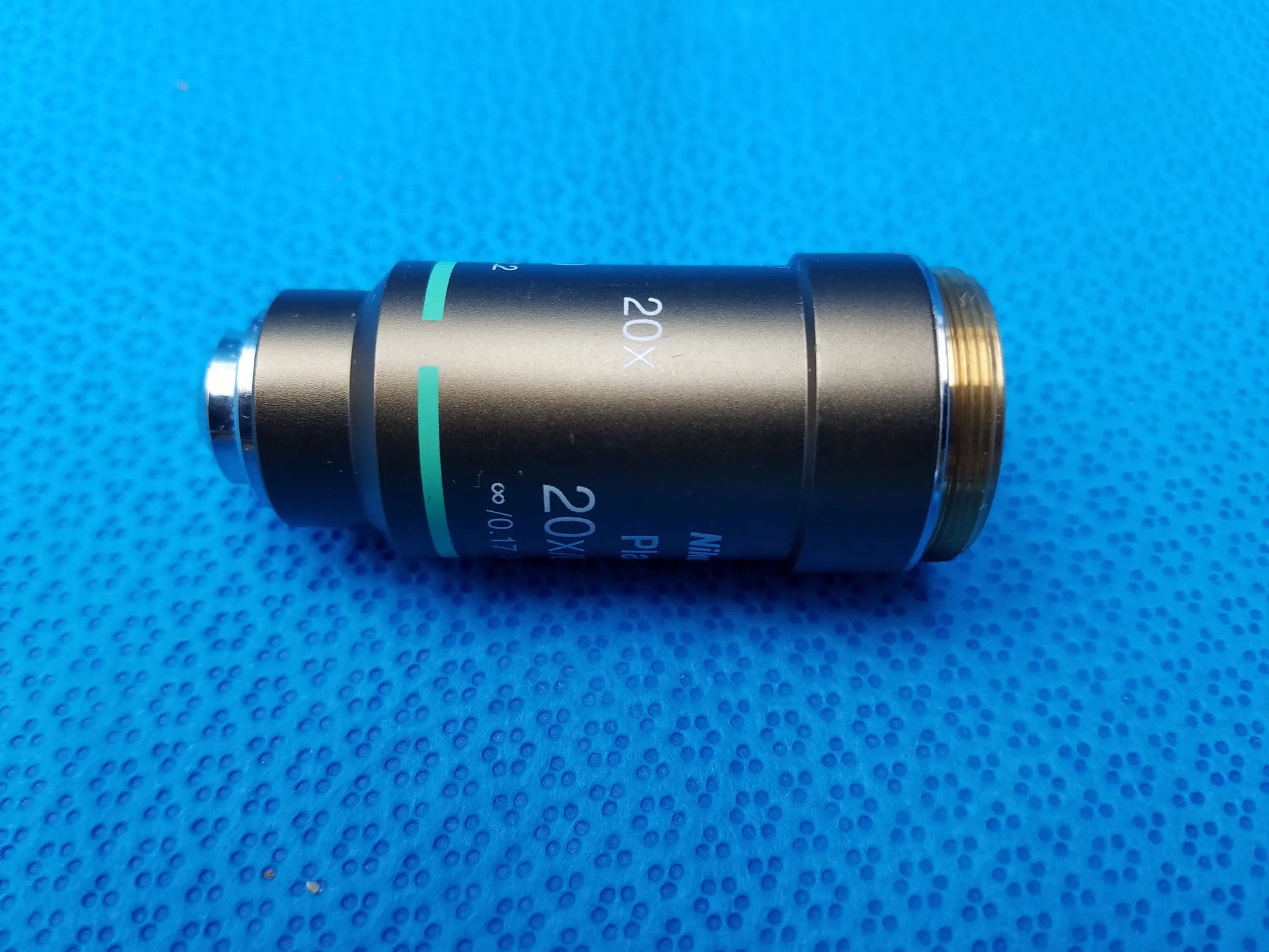 Black Nikon plan 20x microscope objective lens with gold threaded mount and green accent markings for precision use