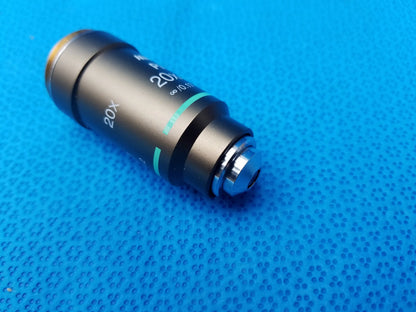 Nikon plan 20x 0.40 metallic microscope objective lens with green accent ring on textured blue surface