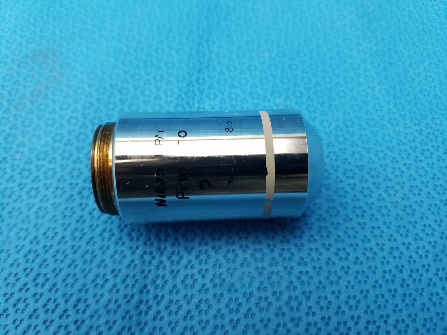 Silver Nikon Plan 2x microscope objective lens with gold threaded mount and black engravings for compatible Nikon microscope systems