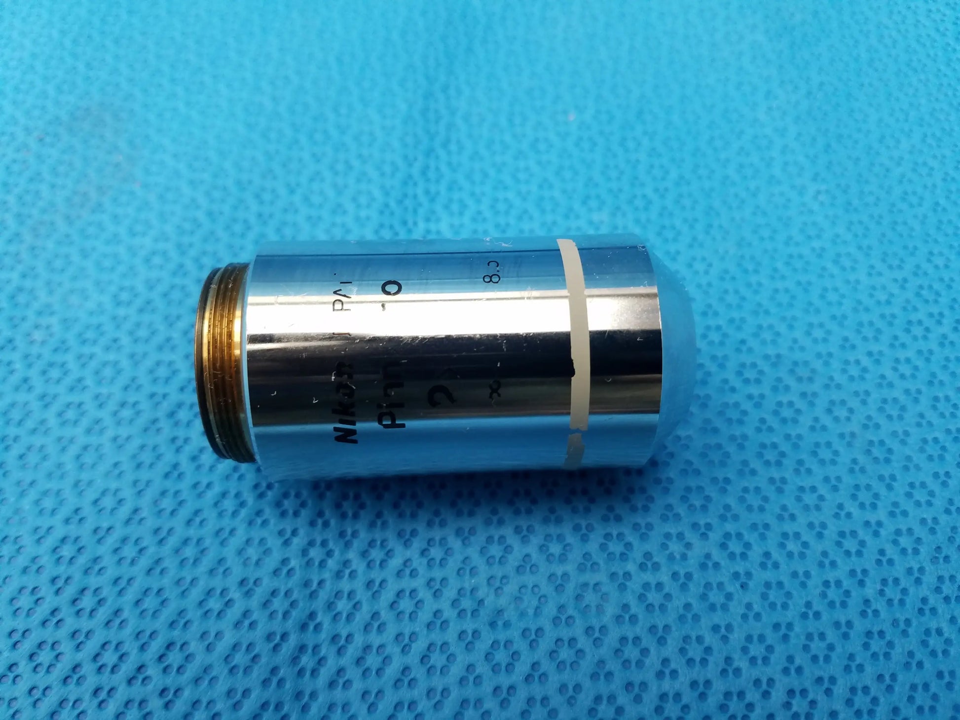 Silver Nikon Plan 2x microscope objective lens with gold threaded mount and black engravings for compatible Nikon microscope systems