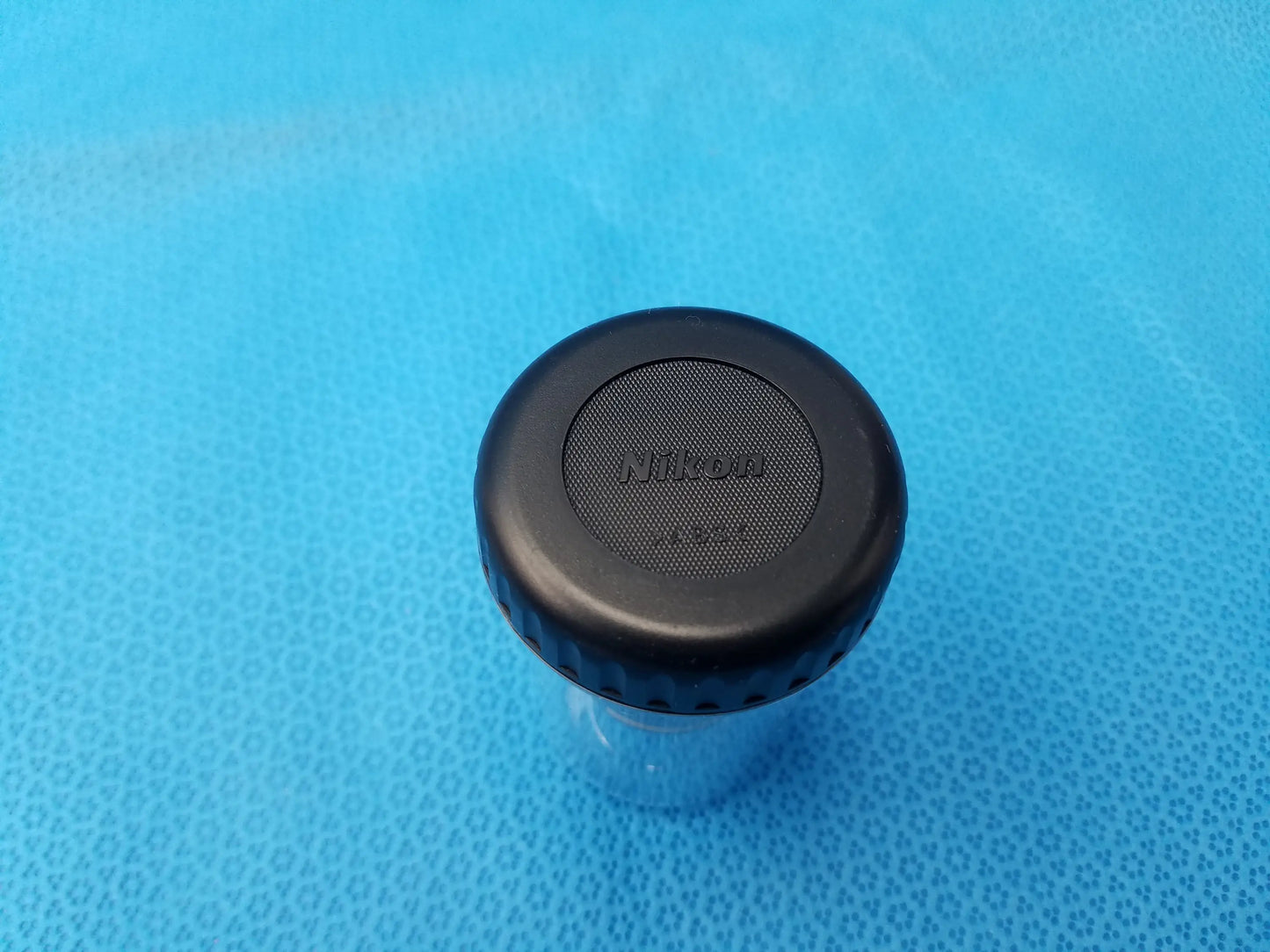 Black nikon lens cap with textured surface and ridged edge for plan fluor microscope objective with 16 mm working distance