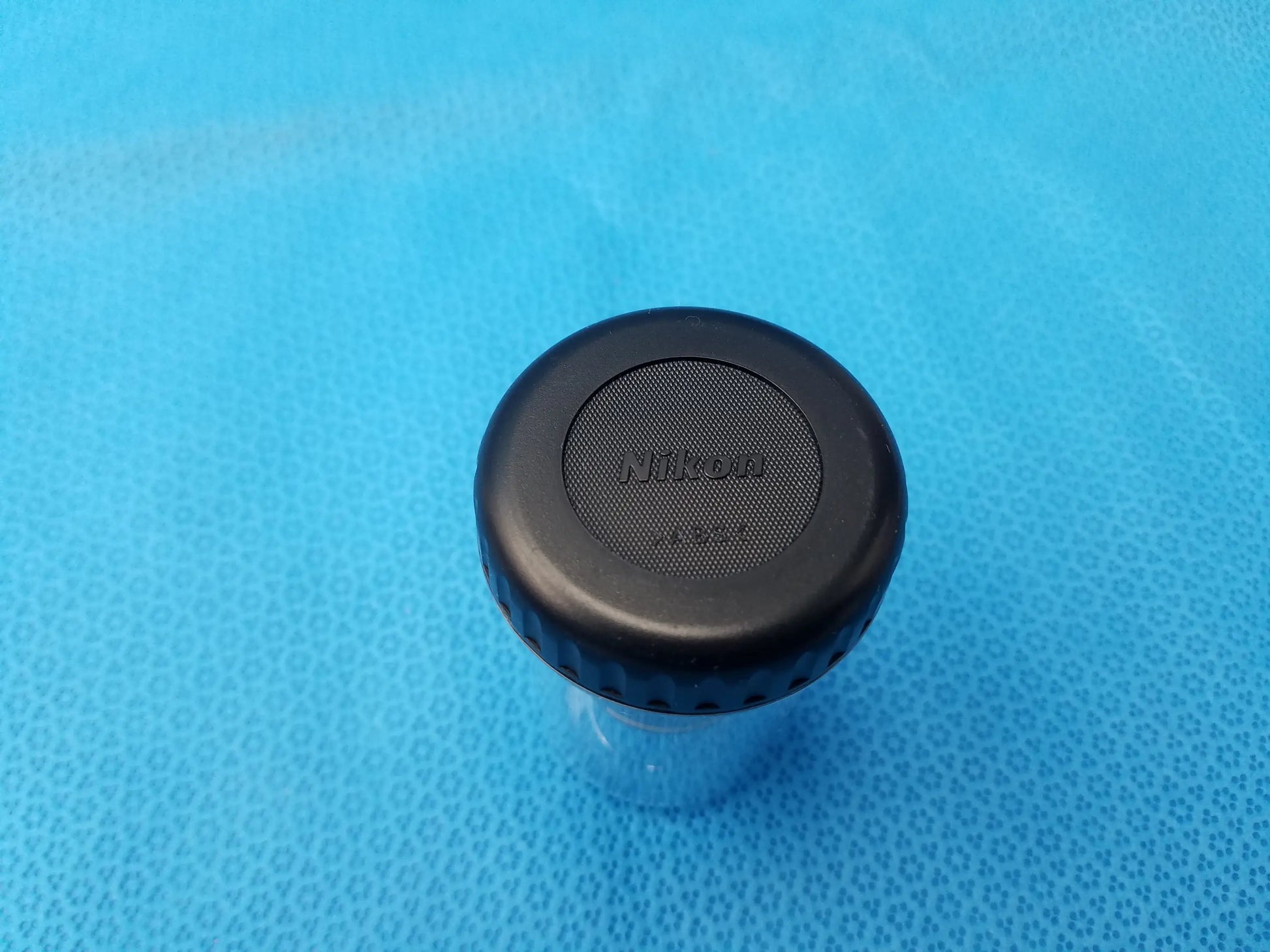 Black nikon lens cap with textured surface and ridged edge for plan fluor microscope objective with 16 mm working distance