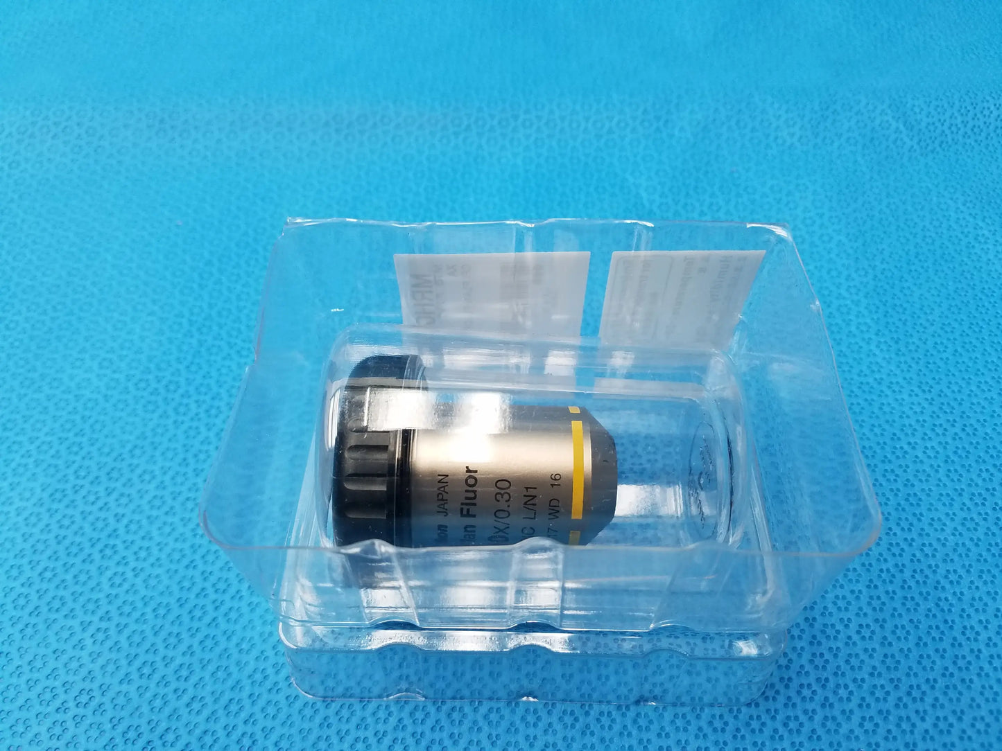 Silver and black nikon plan fluor microscope objective lens with yellow accent band and 16 mm working distance