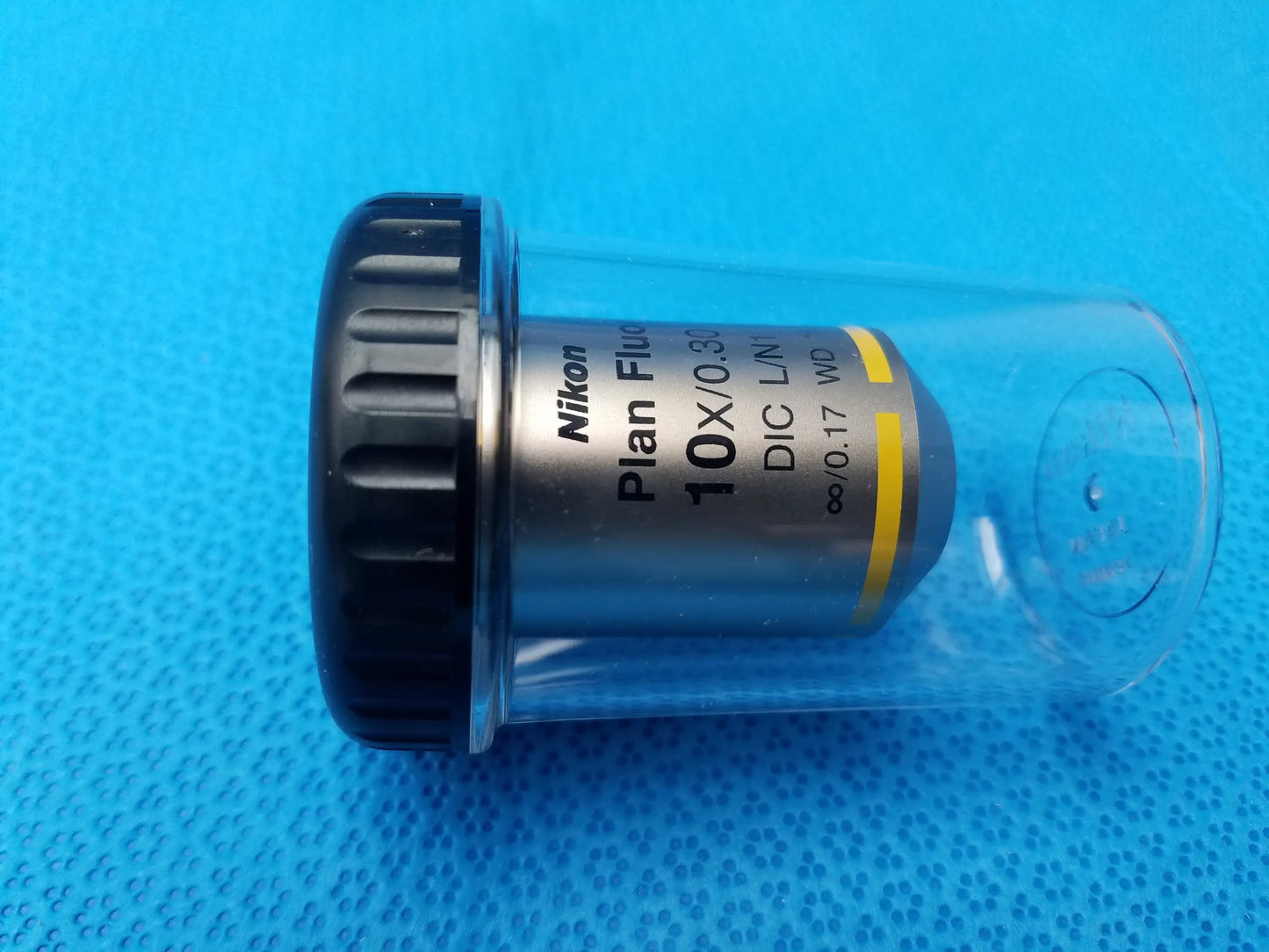 Nikon plan fluor microscope objective lens with black knurled focusing ring silver body and 16mm working distance in clear tube