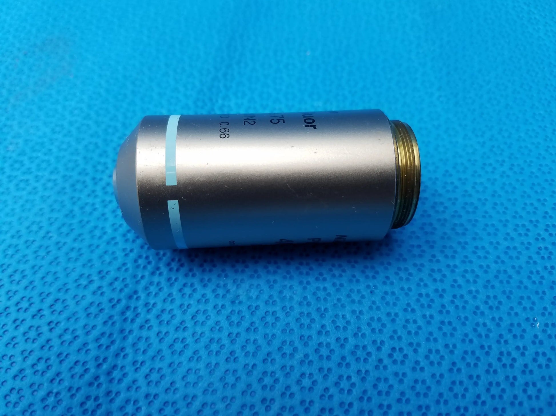 Silver metallic plan fluor microscope objective lens with gold threaded end and light blue markings compatible Nikon