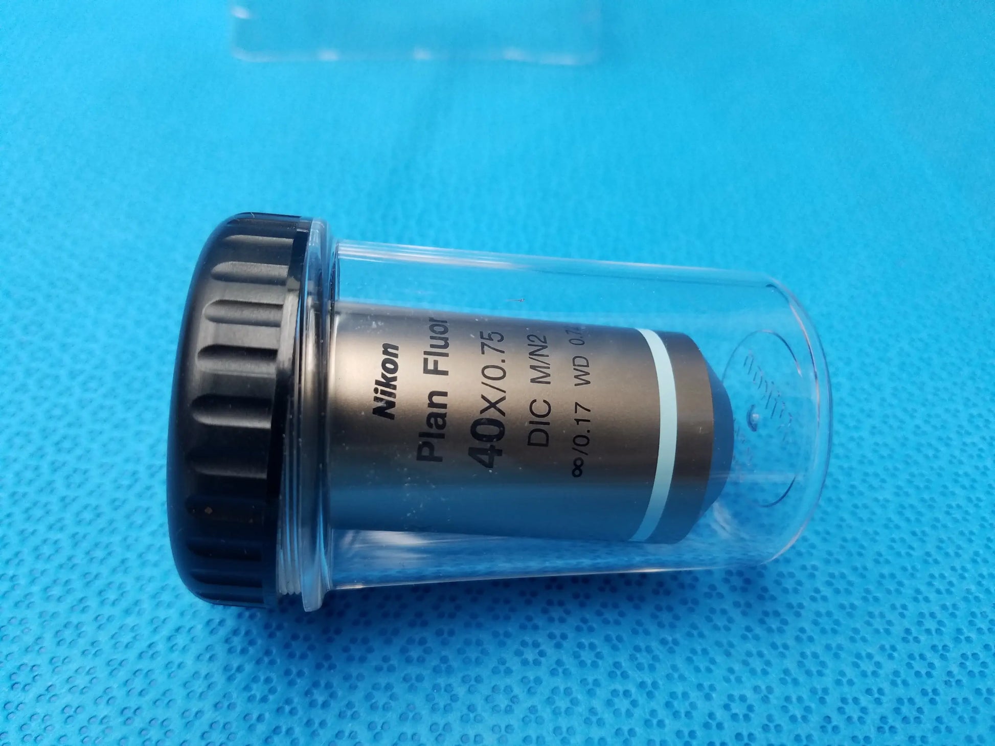 Nikon plan fluor 40x 0.75 microscope objective lens with black knurled cap in clear protective casing compatible Nikon