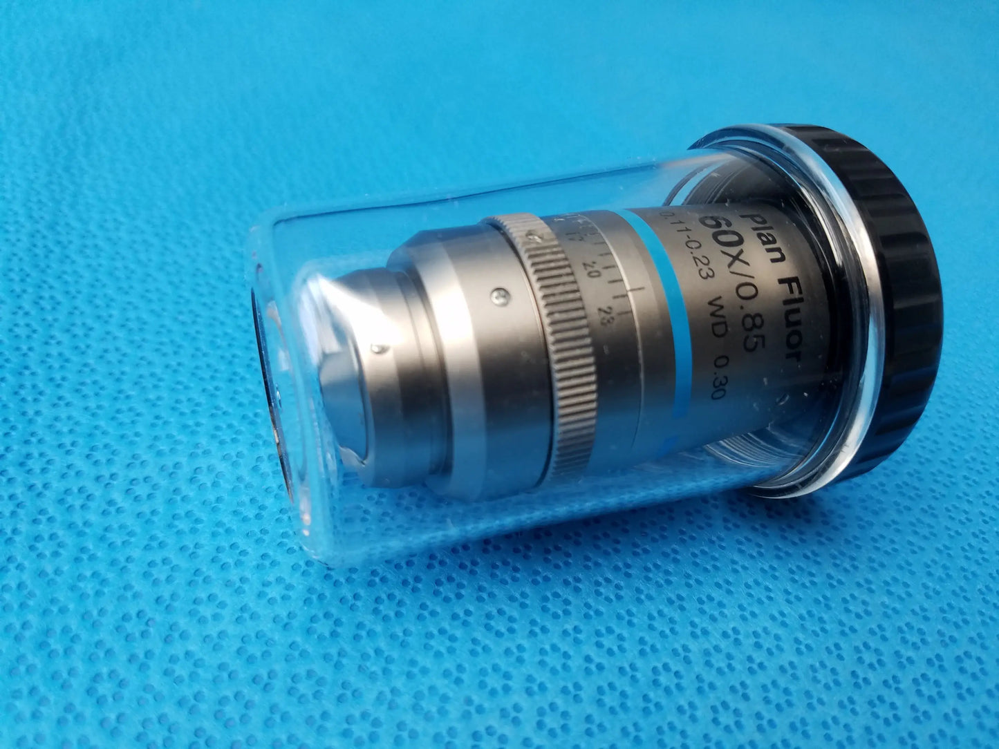 Silver metallic nikon plan fluor 60x 0.85 microscope objective with black knurled ring encased in protective plastic tubing