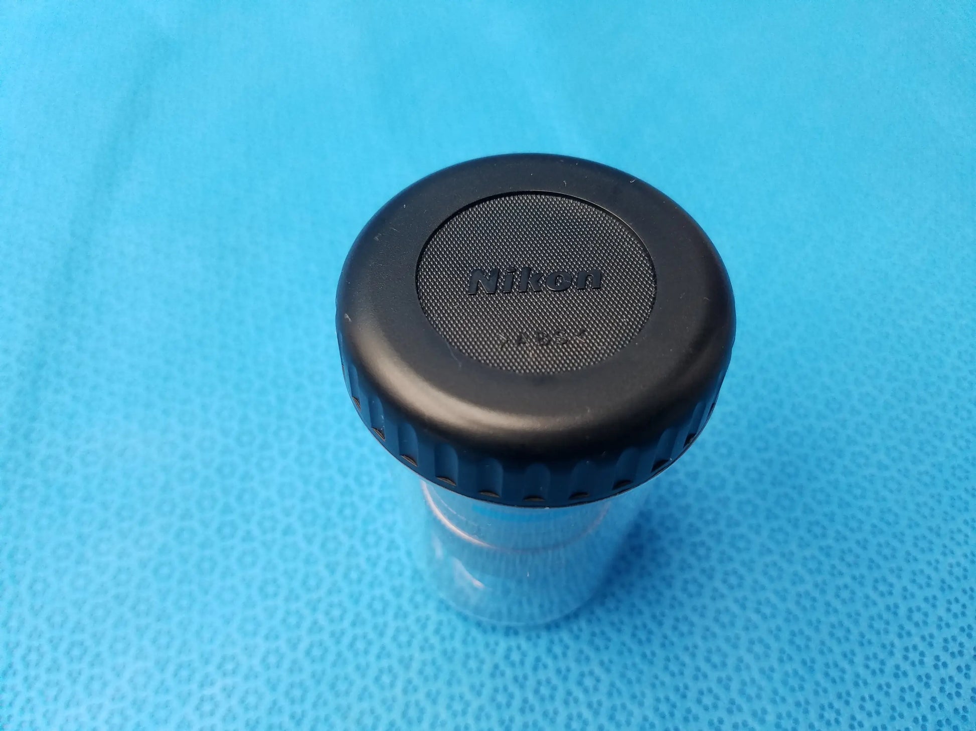 Black Nikon lens cap with textured grip and silver logo for compatible Nikon plan fluor microscope objective MRH00602